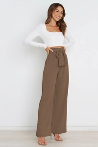 Detail of high waisted wide leg pants in brown with decorative waist bow tie