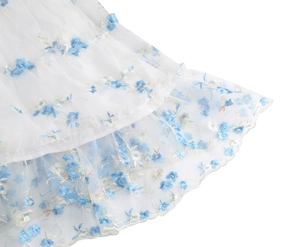 Detail view of mesh embroidery dress with blue floral patterns and layered ruffles