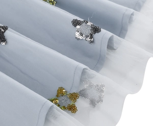 Macro view of sequin butterfly embroidery on light blue tulle fabric for a party dress
