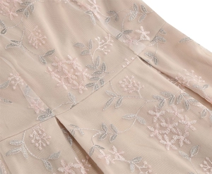 Détail de la broderie florale délicate sur tissu en maille beige pour robe sans manches