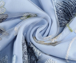 Macro detail of delicate floral embroidery on light blue mesh fabric and satin lining