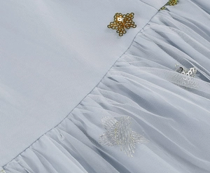 Detailed macro view of light blue mesh fabric with golden star sequins and silver embroidery
