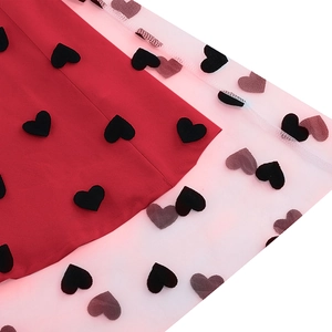 Detail of red cocktail dress with white mesh overlay and black flocked heart embroidery