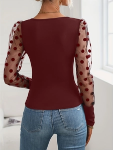 Detail view of burgundy knit top featuring black sheer mesh sleeves with polka dots