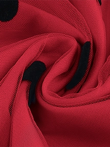 Detail of red mesh fabric featuring classic black polka dot pattern and soft drape texture