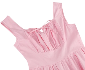 Détail d'une robe rose sans manches avec encolure en U froncée, petit nœud et découpe