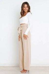 Detail shot of high-waisted beige wide-leg trousers with a stylish front bow tie decoration