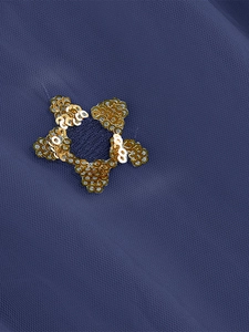 Detail of dark blue tulle dress featuring gold star sequin appliques and fine mesh texture