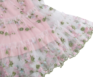 Detail view of the floral embroidery and layered mesh fabric on the pink dress hemline