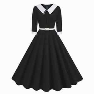Detail of the elegant black dress featuring a wide white contrast collar and belted waist