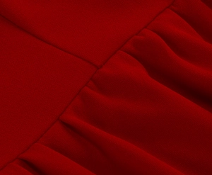 Close-up of deep red chiffon dress fabric with refined stitching and pleated details