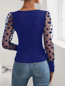 Close-up of dark blue knit top featuring sheer mesh sleeves with polka dot patterns