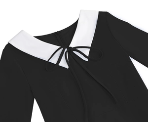 Detail of elegant black dress with white Peter Pan collar and delicate ribbon bow tie