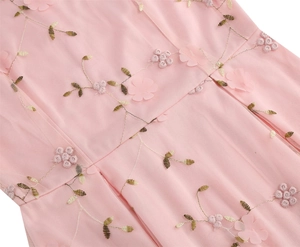 Détail de robe en tulle rose avec broderies florales 3D et fils dorés