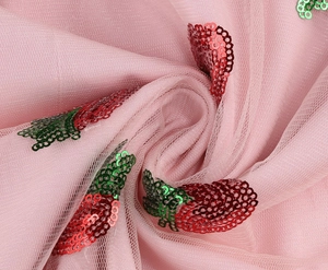 Close-up of pink mesh fabric with detailed strawberry sequin embroidery on cocktail dress