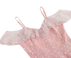 Détail de la broderie et du décolleté à volants sur une robe en dentelle rose