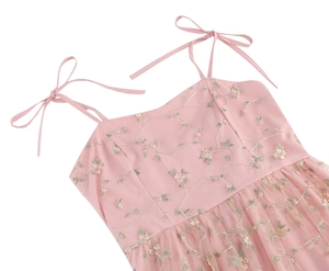 Detail view of pink tulle dress featuring floral embroidery and ribbon shoulder straps