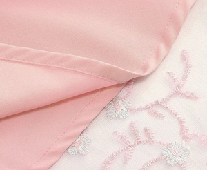Détail de broderie florale rose sur tissu en maille blanche transparente de la robe