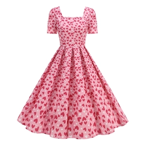 Détail d'une robe vintage à col carré avec imprimé coeurs rouges sur tissu rose vif