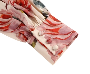 Macro view of floral puff sleeve cuffs with three fabric-wrapped buttons on a V-neck dress