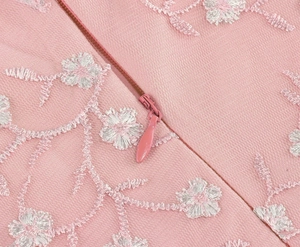Vue détaillée des broderies florales blanches et de la fermeture éclair rose sur robe