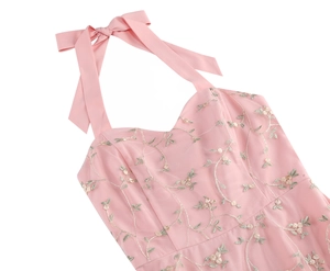Detail of light pink mesh dress featuring delicate floral embroidery and a satin bow