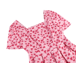 Détail de l'encolure carrée et manches bouffantes sur robe rose à imprimé cœurs