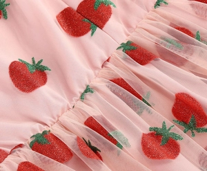 Detail of pink tulle fabric featuring red glitter strawberry prints and fine mesh texture