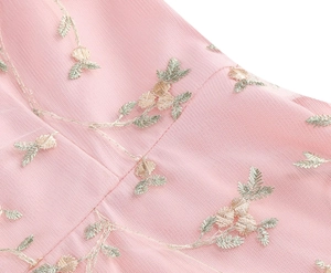 Close-up of delicate floral embroidery on light pink mesh fabric for elegant evening dress
