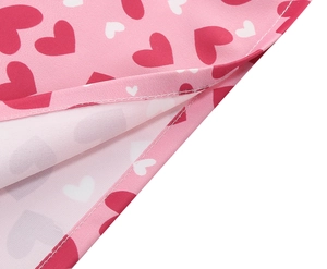 Détail du tissu à motif cœur rose montrant des coutures de qualité sur l'ourlet