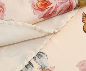 Close-up of lightweight woven fabric with pink rose prints and neat hem stitching