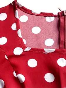 Detailed close-up of square neckline and invisible zipper on red polka dot dress