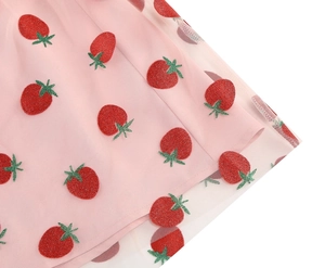 Detail of pink mesh dress featuring strawberry glitter prints and soft tulle texture