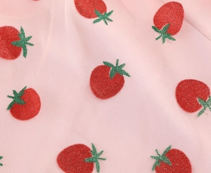 Detail of pink mesh fabric with glittery red strawberry embroidery and fine net texture