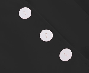 Detail view of white resin buttons on high-quality black fabric of summer dress