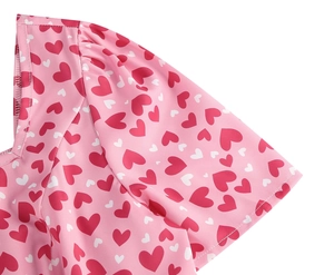 Gros plan sur les manches bouffantes roses avec motifs cœurs rouges et tissu plissé