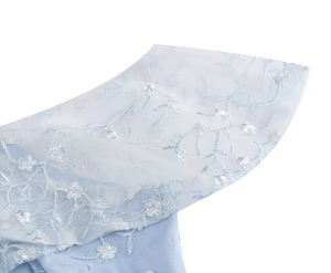 Détail du tissu en maille bleu clair avec broderie florale délicate et dentelle