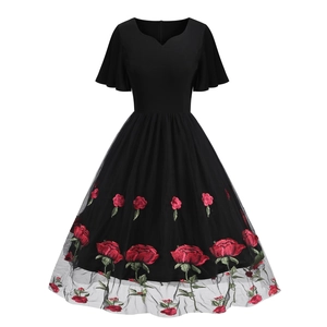 Detail of red rose embroidery and black mesh overlay on a retro cocktail dress skirt