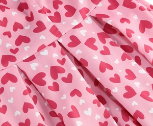 Gros plan sur tissu plissé rose avec motifs de cœurs rouges et blancs pour robes