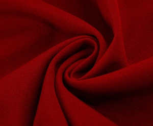 Close-up of dark red crepe fabric texture with elegant draping and matte finish
