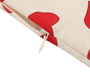 Detail of invisible zipper closure on cream fabric with red heart print patterns