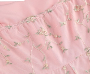 Detailed macro view of delicate gold floral embroidery on pink mesh and tulle fabric