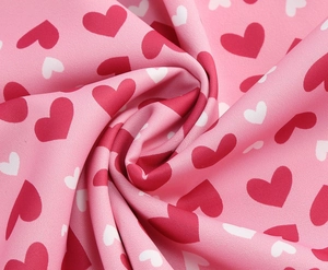 Détail rapproché du tissu rose doux avec des motifs de cœurs rouges et blancs plissés