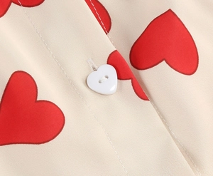 Detail of red heart prints and a heart-shaped button on a beige vintage short-sleeve dress