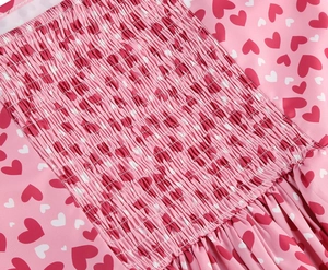 Détails de la robe plissée rose avec motifs de cœurs rouges et tissu élastique froncé
