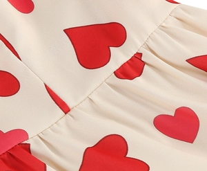 Detailed close-up of red heart print on cream fabric with fine pleated stitching