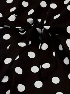 Detail of elegant black and white polka dot dress with a tied bow and smooth fabric