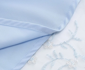 Détail de la broderie florale bleu clair sur résille blanche avec tissu tissé lisse