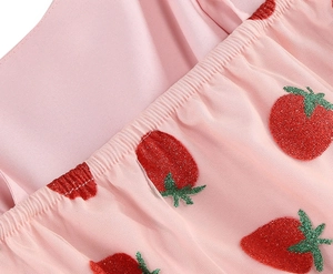 Close-up of pink mesh fabric with glitter strawberry embroidery and elastic stitching