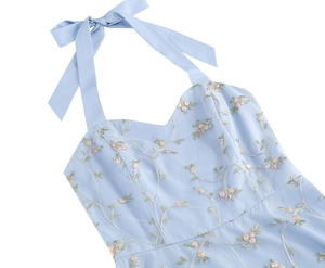 Close-up of halter neckline with large bow and delicate floral embroidery on blue mesh